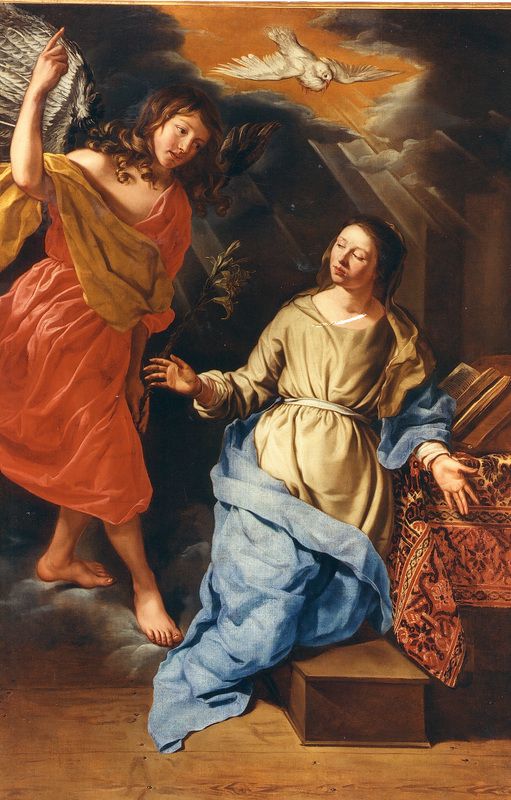 An oil painting of the Annunciation. Mary, in a tannish robe and blue cloak, turns away from the table where she kneels reading to look up at the Angel Gabriel. The winged angel, who has long brown hair and wears a red robe with a yellow-gold cloak, holds a stalk of lily in his left hand. With his right hand he points skyward. Between them, above their heads, in an opening in the clouds, is the Holy Spirit in the form of a white dove.