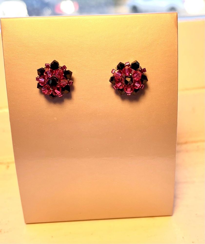 A beaded earring fashioned to look like a flower. Black and pink