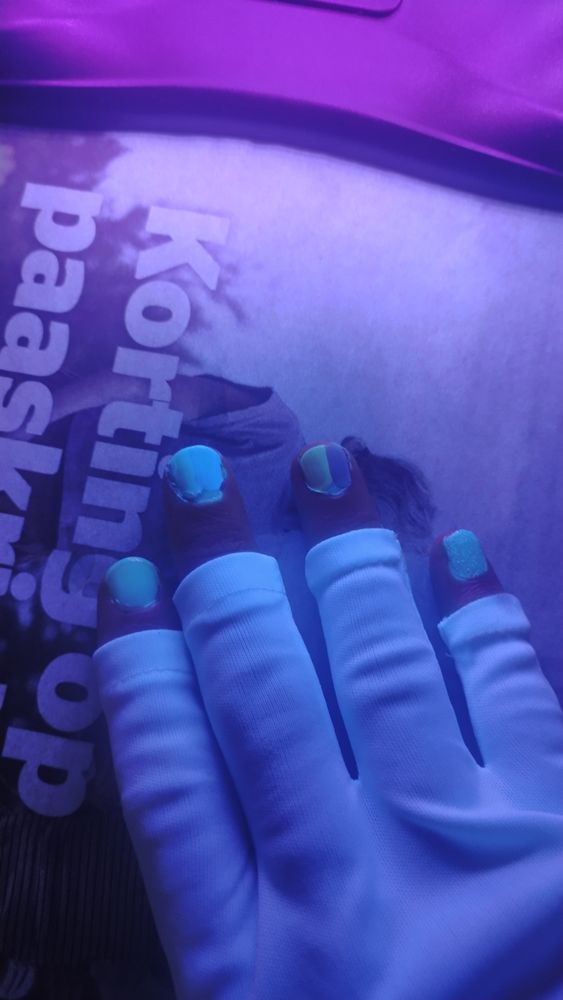Picture of my lil fingies in a nail glove, under a UV light. Each nail painted different from the rest. 
A clear coat, two different blues, a red and yellow, and the last is a glitter coat. All topped with the same UV reactive top coat 

The blues, yellow, and not pictured black and whites were the best, and I might follow that up with more testing later 