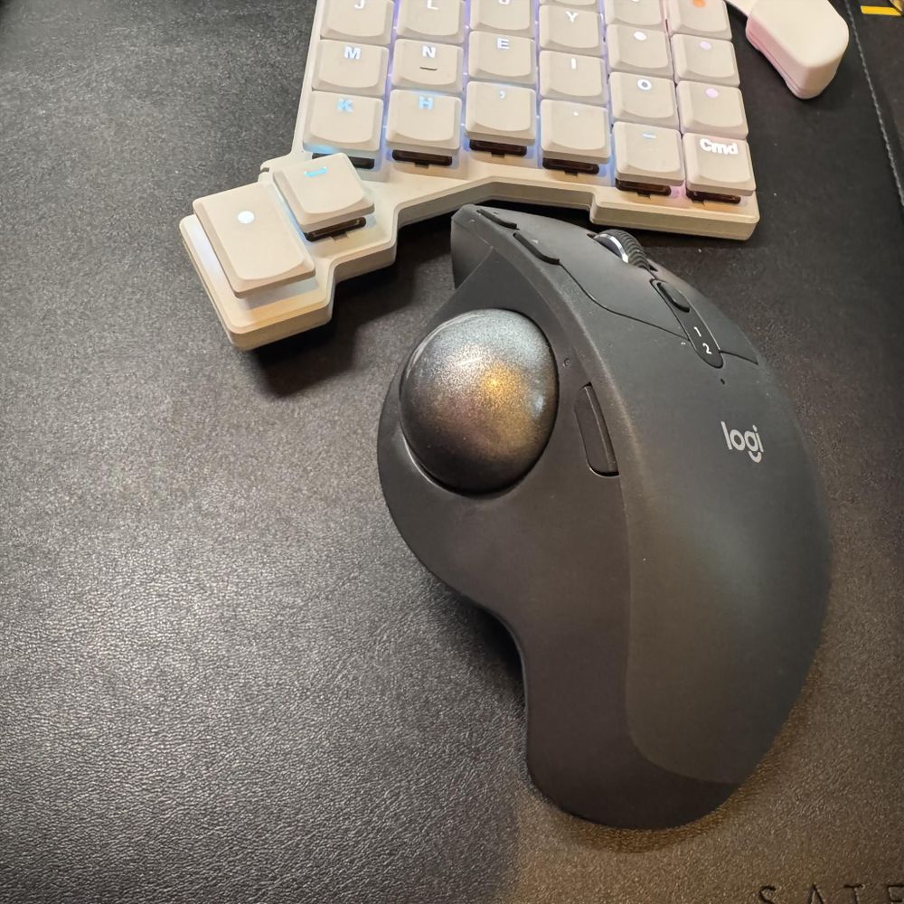 The Logitech MX Ergo S Advanced, sitting below one half of the ZSA Voyager.