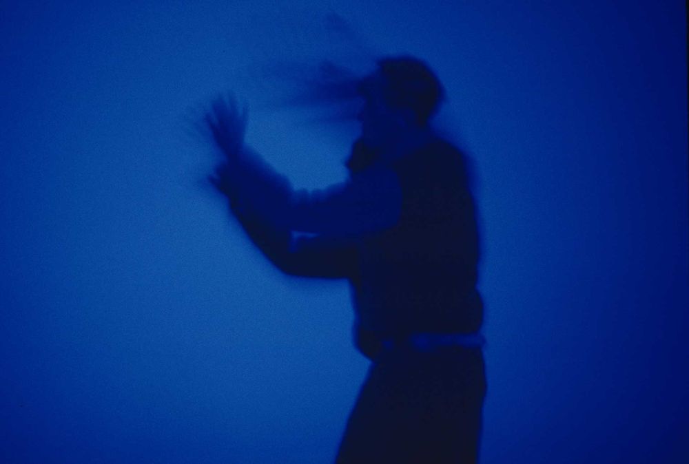 A figure silhouetted against a rich blue backdrop
