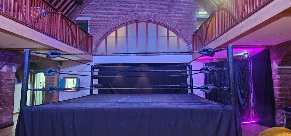 A view of the ring prior to SCW's second show, Forged By The Fates. The photographer is in the second row of the seating for the show, which sits on one side in a theatre style configuration. The wrestlers entrance can be seen on the right. The balconies are unused.
