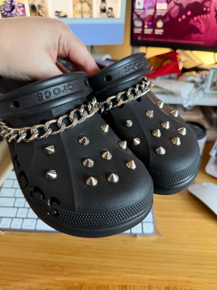 Black crocs with a metal chain and silver spikes added to them 