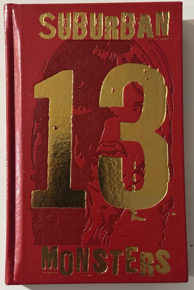 A hardcover book with the title stamped in gold foil: 13 Suburban Monsters