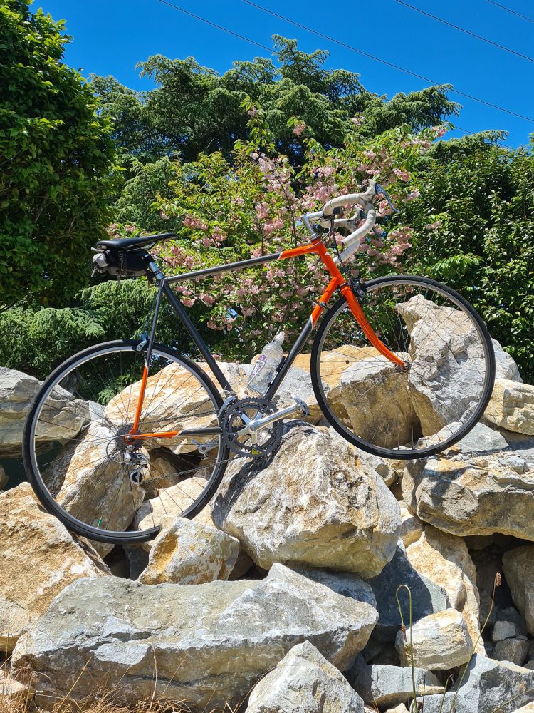 An orange and silver road bike positioned in a pile of boulders 