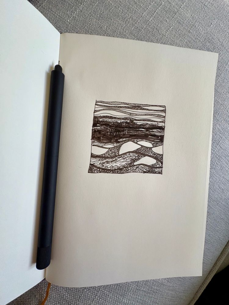 An open sketchbook on page one. There’s a pen lying in the crease of the book. On the right-hand page, you’ll find an illustration of a river scene in black ink. The waves are depicted as cross-hatched swirls that move from left to right. The scene extends upward, crossing a riverbank and traversing dark fields. The background sky is characterized by linear cloud lines.