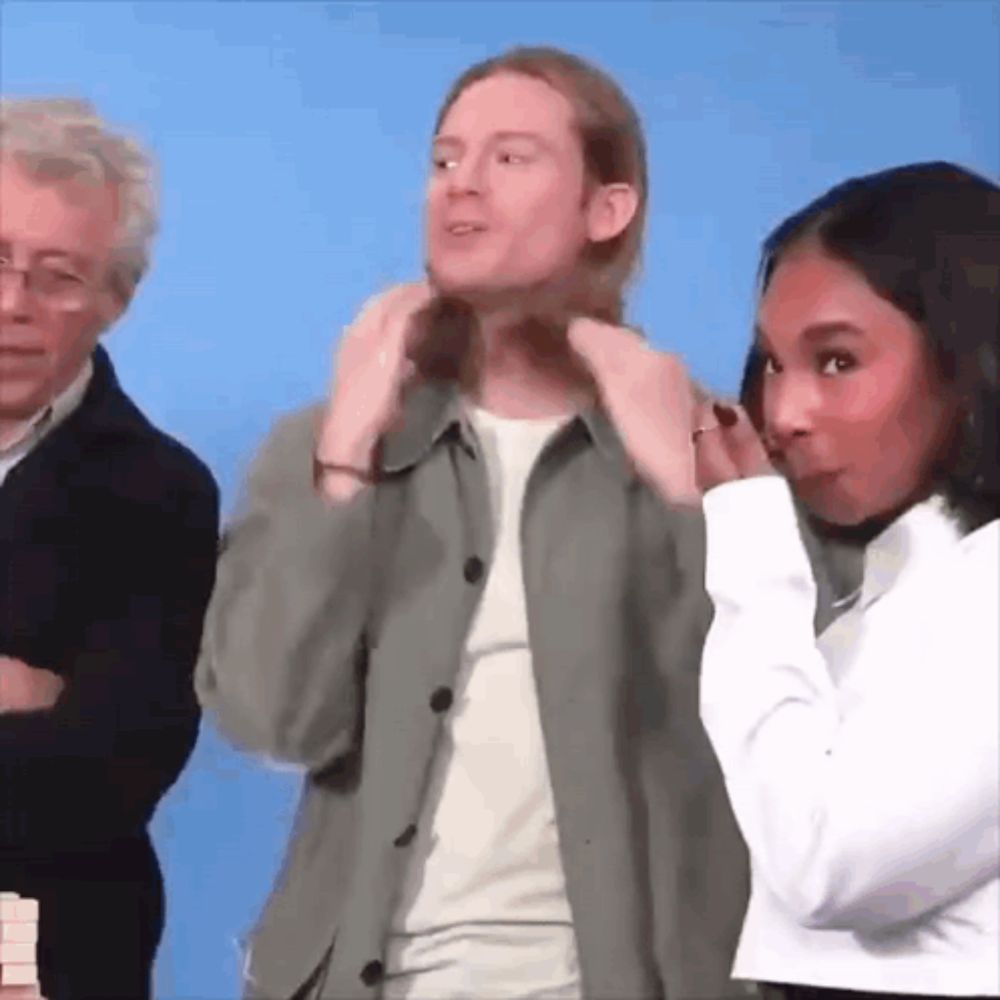 a man and a woman are standing next to each other . the man is adjusting his hair while the woman looks on .