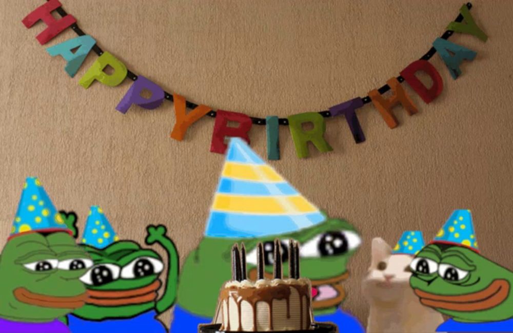 a happy birthday banner hangs above a cake with frogs wearing party hats