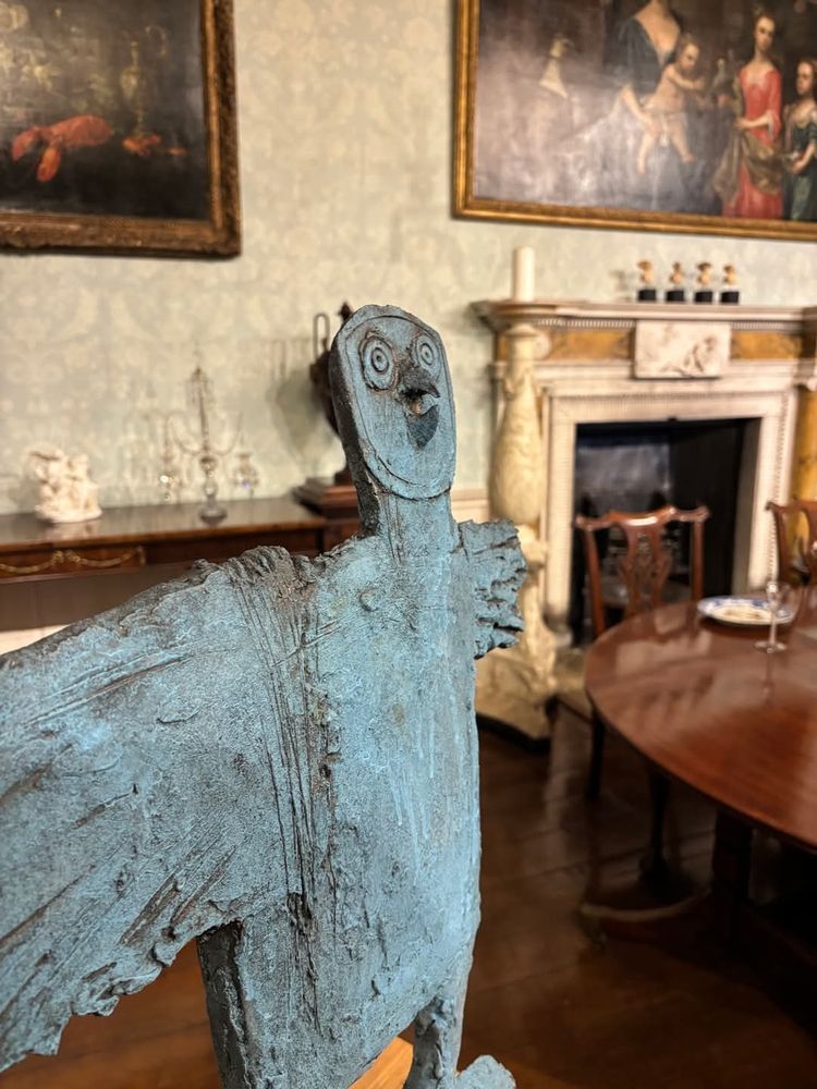  A bird statue stands in a room furnished with a table and chairs, creating a serene atmosphere.