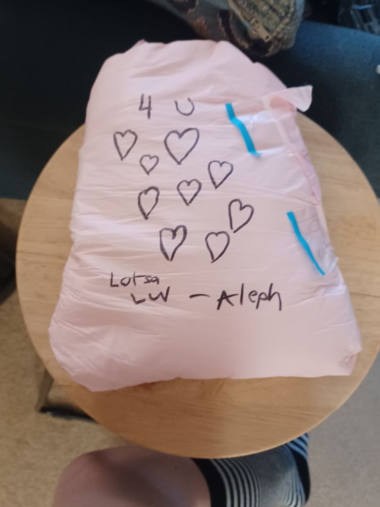 A budled up wet diaper with marker saying "4 you, lotsa luv - Aleph" and many hearts