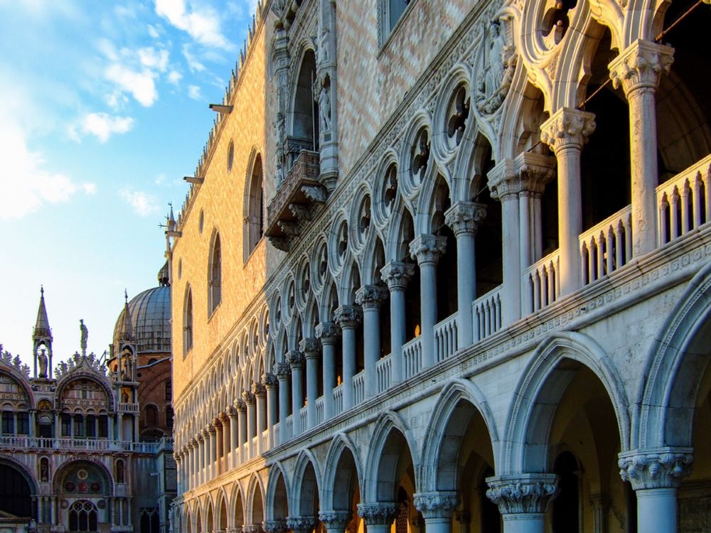 Vista lateral del Palazzo ducale, en la plaza de San Marcos. Tiene una hilera de arcos tanto en la planta baja como en la primera. La fachada tiene ladrillos que forman un mosaico muy bonito. Al fondo se ve el lateral de la basílica de San Marcos.