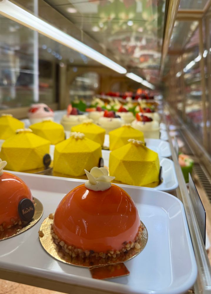 Delicious colorful cakes, by the dozen, in a glass shop display