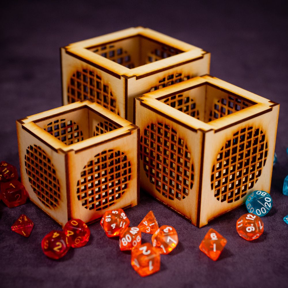 Three different sizes of wood dice jails sitting together on purple fabric with dice scattered around