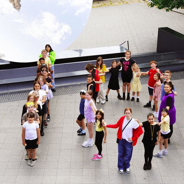 A group of young people standing in the shape of a 10 in front of the Sky Mirror at Nottingham Playhouse.