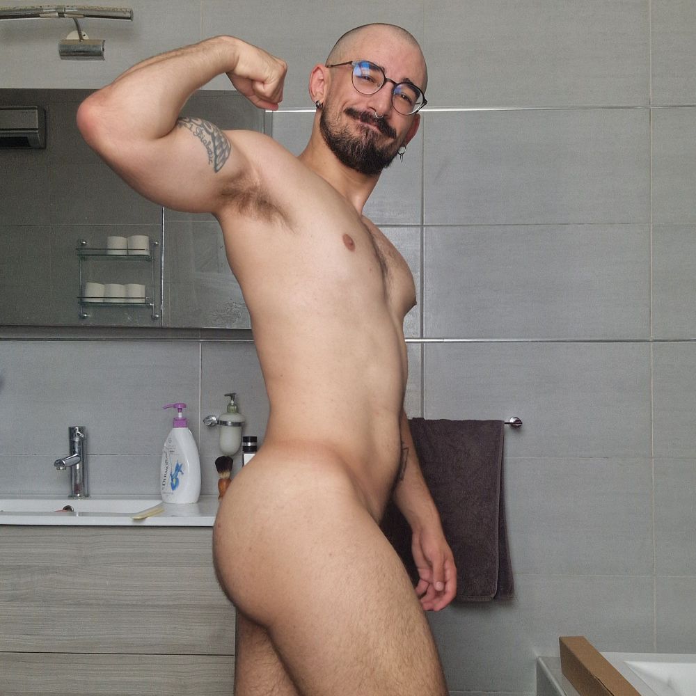 Dizzy naked, flexing his right arm and giving a side profile of his ass