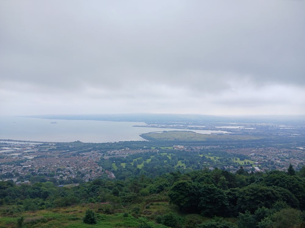 View of Béal Feirste from top of Beann Mhadagáin with the city and suburbs stretching round Loch Lao/Belfast Lough