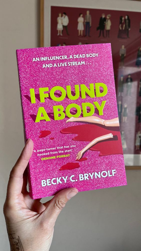 A copy of I Found A Body by Becky C. Brynolf. It shows a pink sparkly cover with broken Barbie doll parts (a leg and a snapped off arm) lying in a pool of red blood. The tagline reads: “An influencer, a dead body and a live stream…” The title is lime green and there is a quote that reads “A page turner that has you hooked from the start” by Oenone Forbat.
