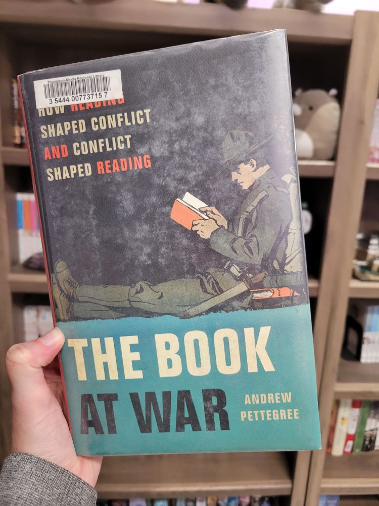 A hand holds a copy of the book The Book At War by Andrew Pettegree
