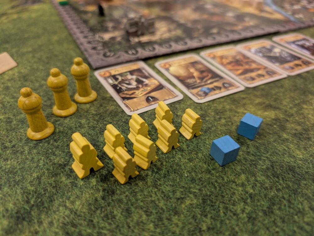 Three yellow pawns (master builders), 8 yellow worker meeples (1 larger = 5), 2 metal resource cubes, some craftsmen cards. 