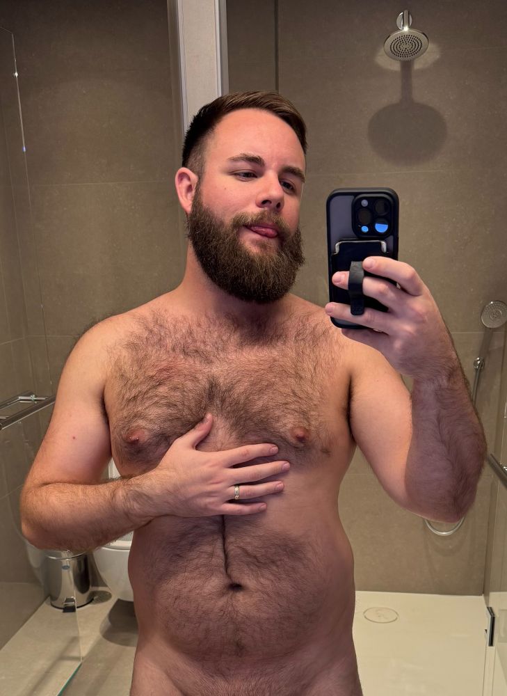 Me, naked in an airport lounge shower, with tongue out and rubbing my hairy chest