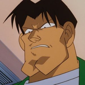 Akira Hirota a menacing looking man with short brown hair wearing a green jack with a white undershirt