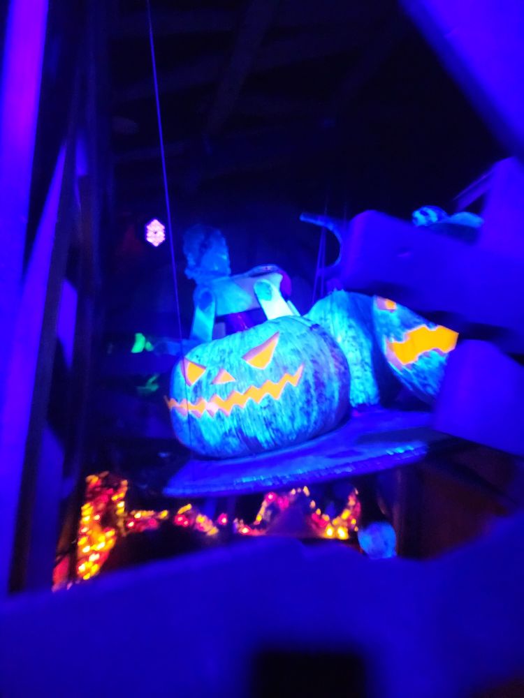 A large jack o' lantern display, illuminated by a UV light making it appear fluorescent blue.