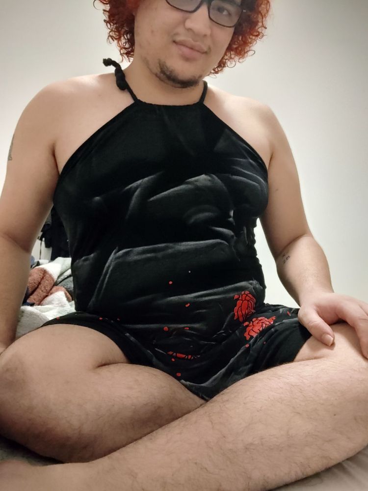 Me sitting on my bed wearing a black rosy dress. Now my legs are visible and they're very yummy