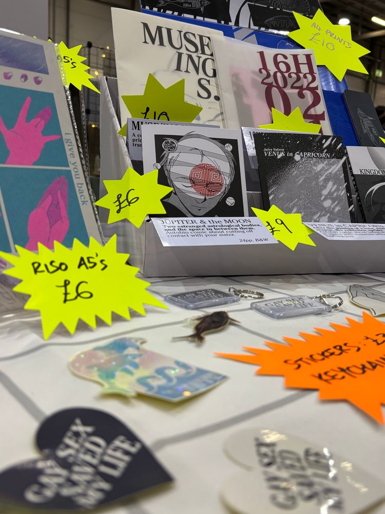 Table-eye view of the zines, stickers and prints at the stall. 