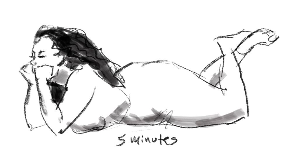 A nude female model lies on her stomach and leans on both elbows. Her hands support her head, and her ankles are crossed.