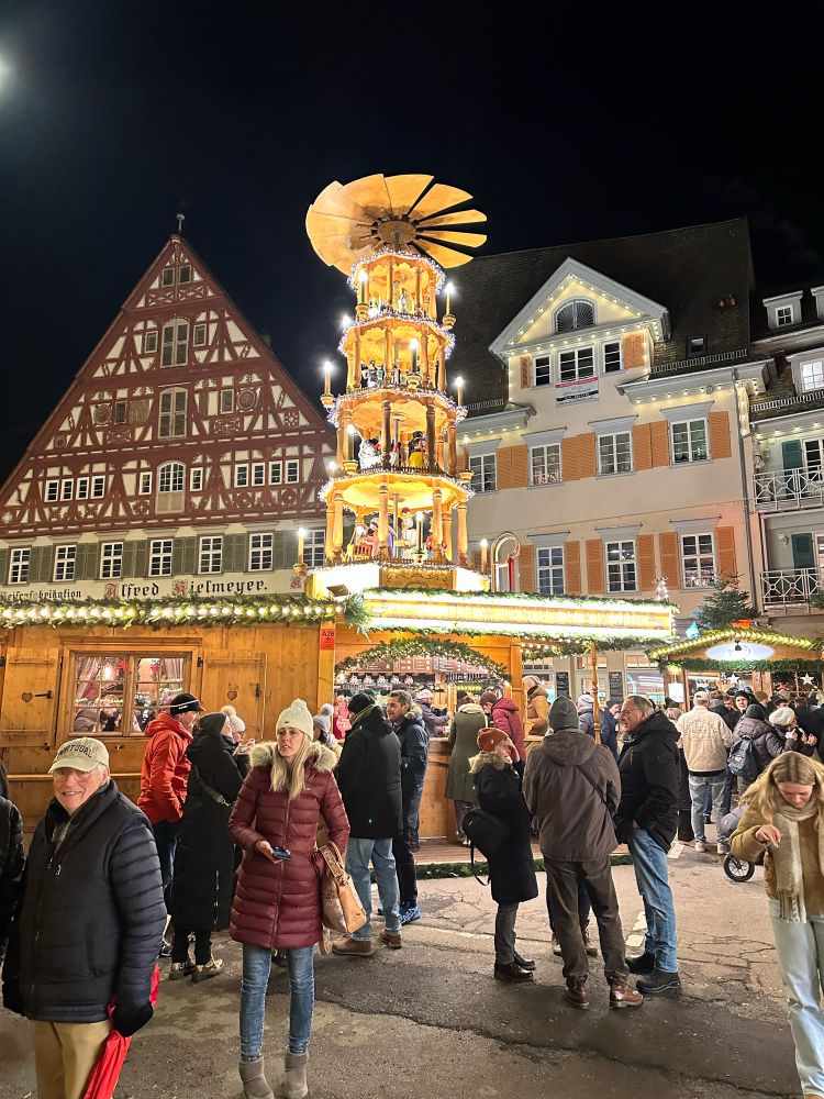 Christmas market with stalls and a big rotating multi storey feature that is lit up in yellow and white lights.