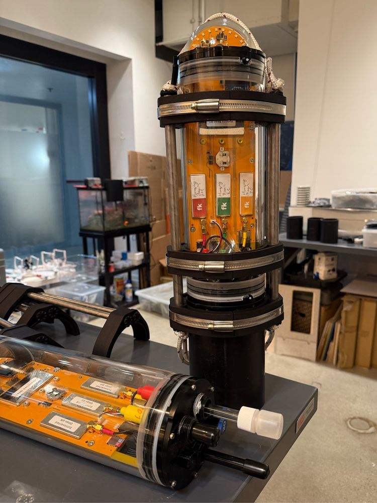 A fully assembled and partially assembled FieldKit.org underwater sensor sitting on a table. The unit measure pH, conductivity, temperature, depth, and dissolved oxygen. 