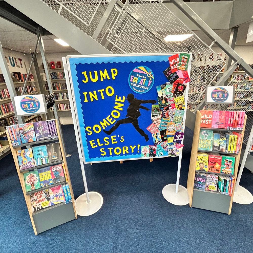 A library display stating “jump into someone else’s story” next to many of the books on display stands.