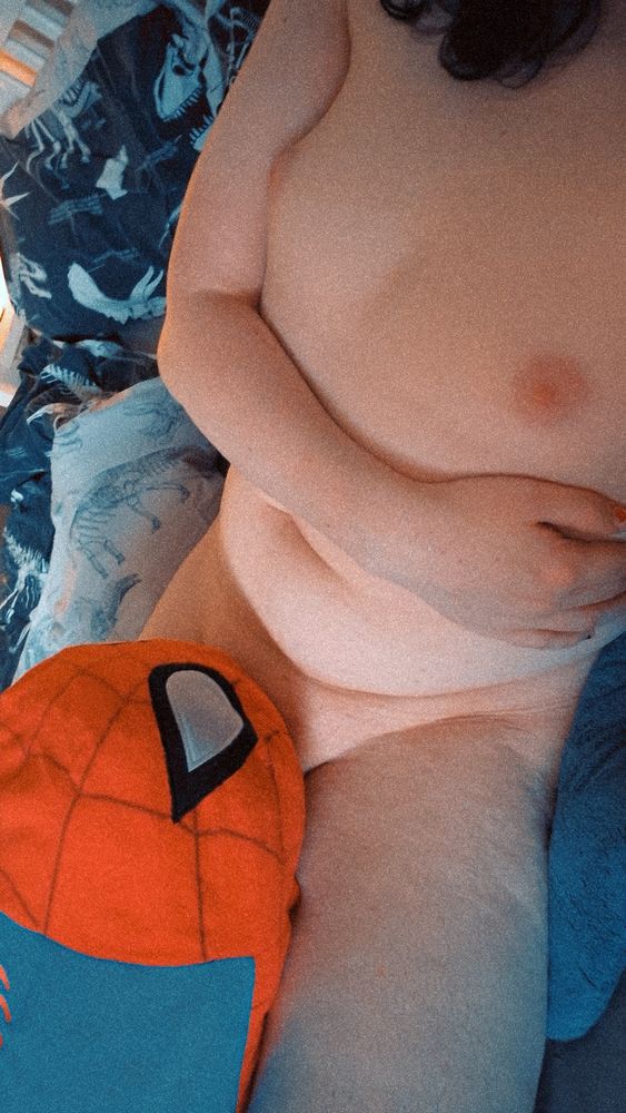 Sharki is laying in bed with her arm across her tummy. Her tits are on show but her dick is hidden underneath a big Spider-Man Tsum Tsum plush.