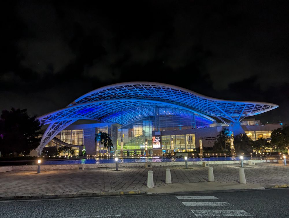 Puerto Rico convention center lit up with blue and green lights at night. 