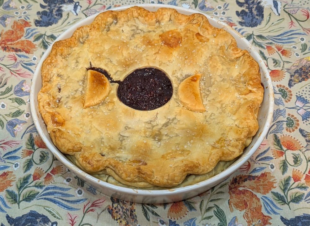 A golden-crusted cranberry-cherry pie in white baking dish.