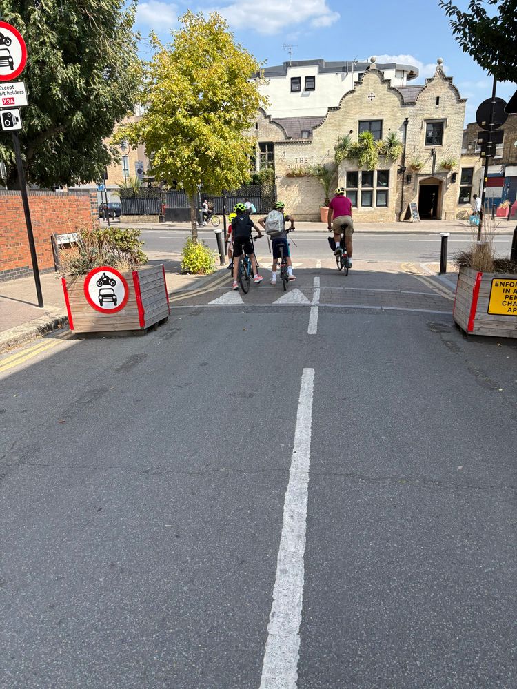 Two adults and three kids on bikes waiting at a junction 