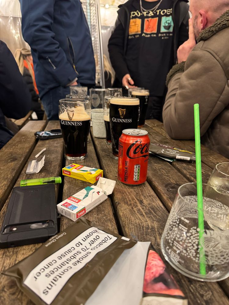 Several pints of Guinness on a picnic table in a beer garden. 