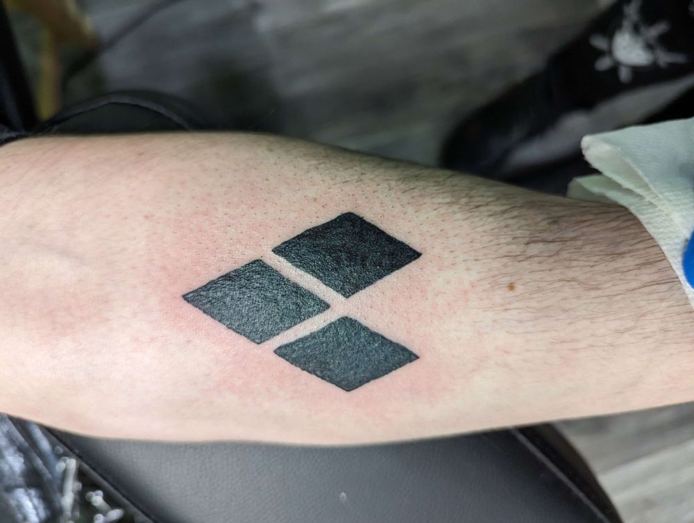 Three tattooed black diamonds, arranged to point towards the inner elbow.