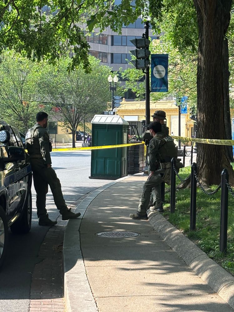Police tape and police blocking the sidewalk and road 