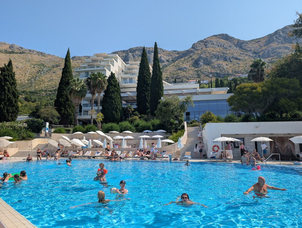 A hotel swimming pool with the hotel in the background.