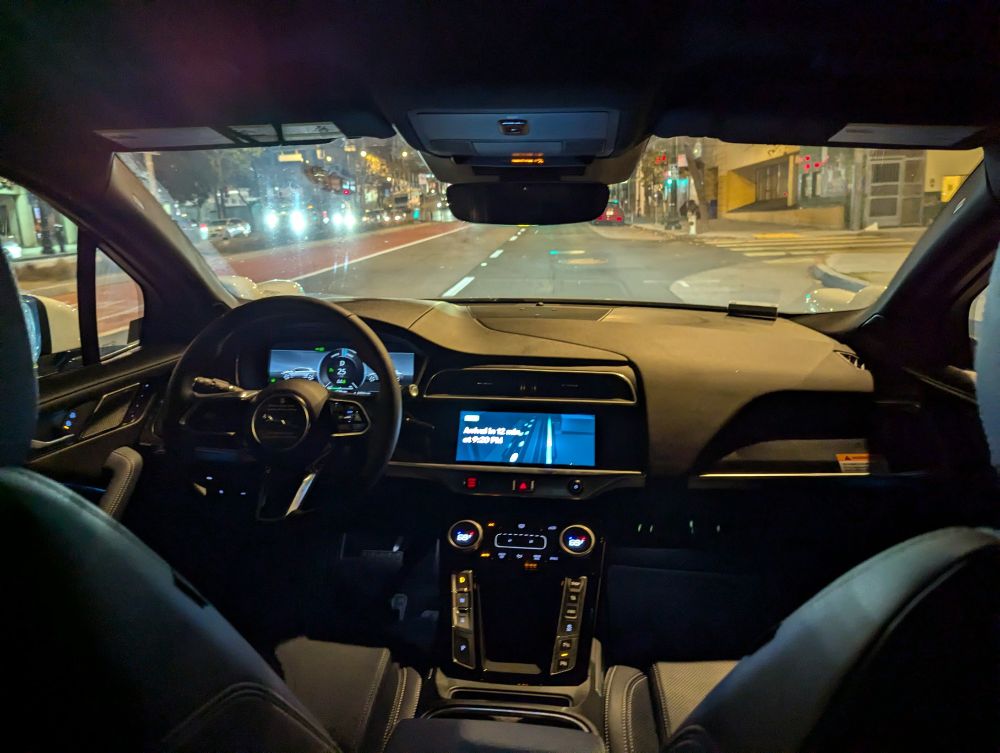 A picture taken from the backseat of a Waymo car, showing no one in either front seat.