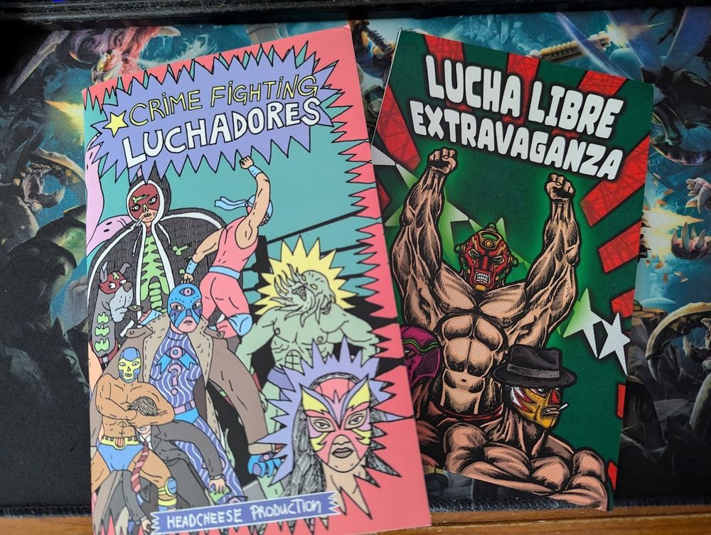 Two booklets, the one on the left is titled "Crime Fighting Lucadores" and the one on the right is titled "Lucha Libre Extravaganza".  Both covers have brightly-colored cartoony lucha wrestlers fighting cartoony villians.
