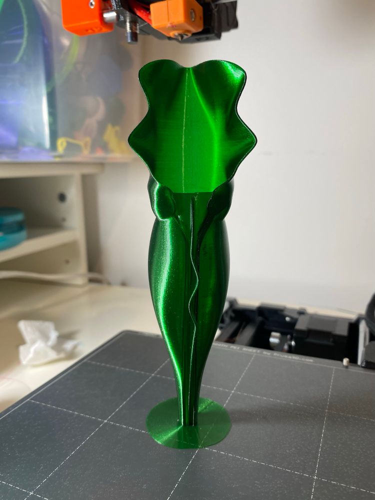 Photo of a dark green, translucent, 3D printed pitcher plant pitcher, standing on a printer bed.