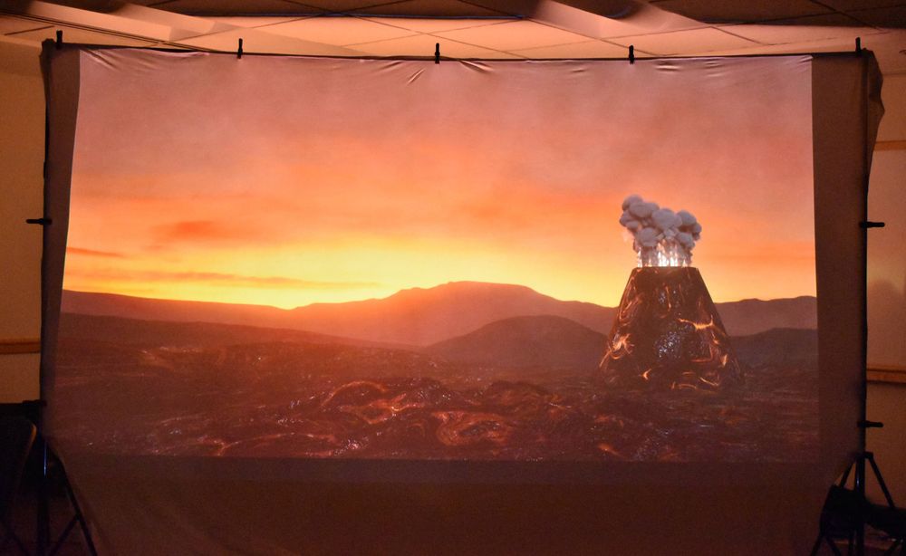 A student-generated image of a volcano erupting agaisnt an orange and yellow sunset.