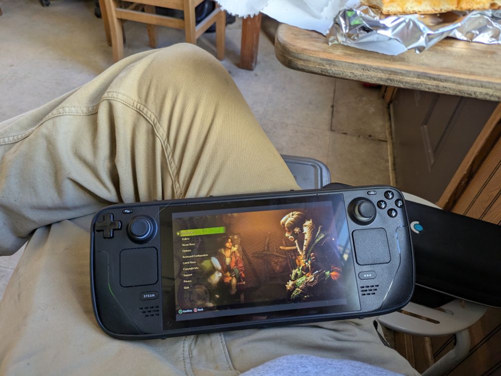 A steam deck sitting in my lap showing monster hunter wilds 