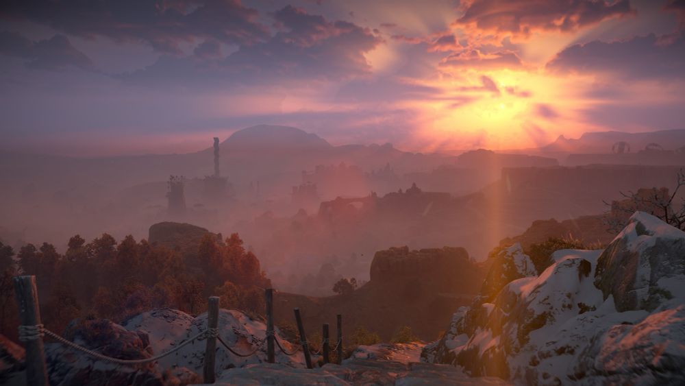 Screenshot from a video game showing a beautiful landscape with the sun setting and casting beams of orange light across the sky