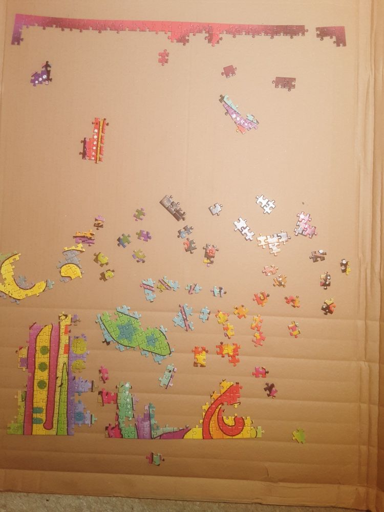 Auf einer Pwppe liegen bunte Puzzelteile, z.T zu Mustern zusammengesetzt. Nicht erkennbar, was es wird