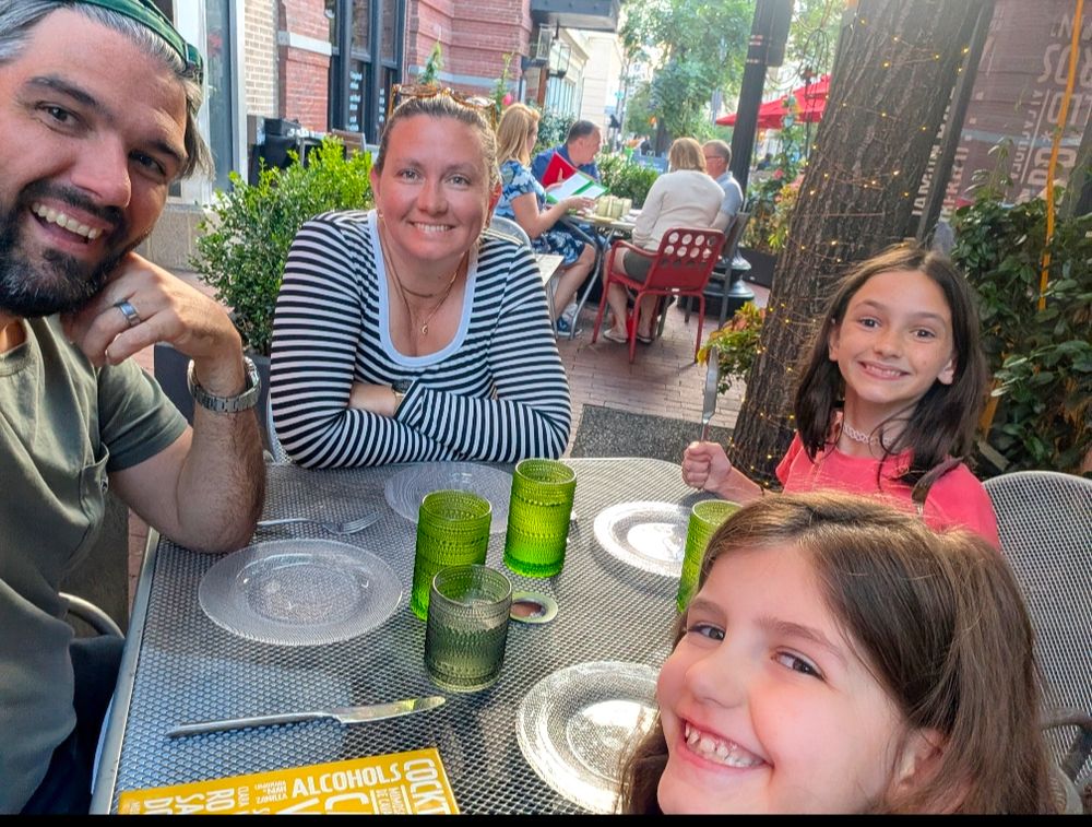 A family smiling out of sheer terror while dining al fresco in Washington, DC in August 2025.