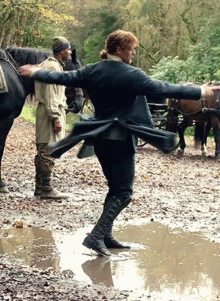 a man in a black coat is standing in a muddy puddle