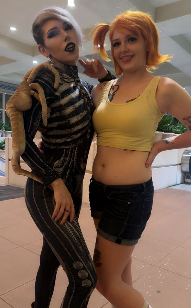 Photo of Lily (FatalGoth) cosplaying as a character from the movie Alien and me cosplaying as Misty from Pokemon. Lily looks very sexy and posed very nice as always. I'm definitely trying, it's one of my better poses but believe me I'm trying very hard. It's overall a good photo. 